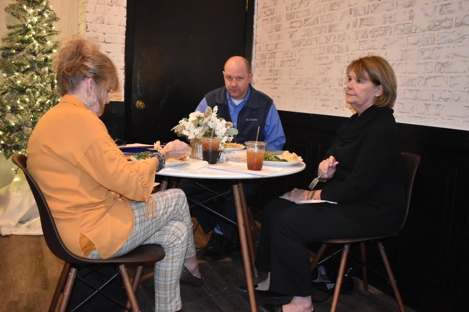 Three people sitting at a table with food.