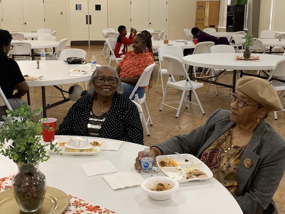 A group of people sitting at tables eating food.