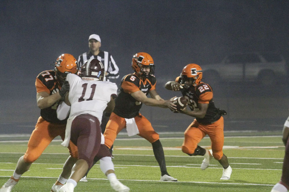 A group of men playing football on a field.