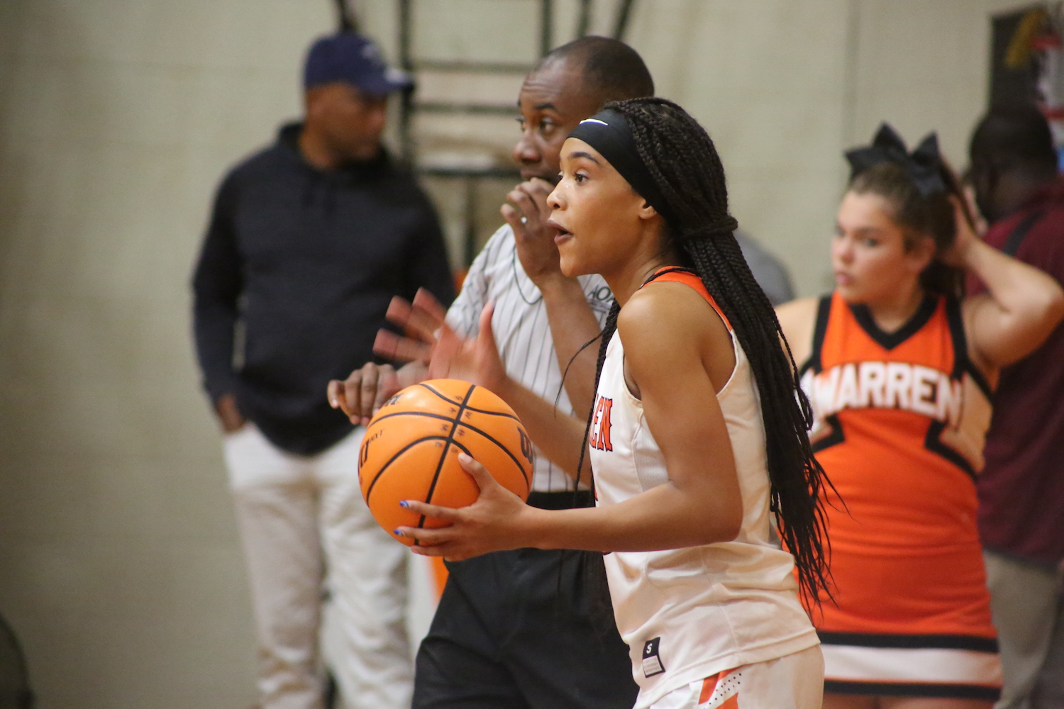 A girl holding onto a basketball while standing next to another person.