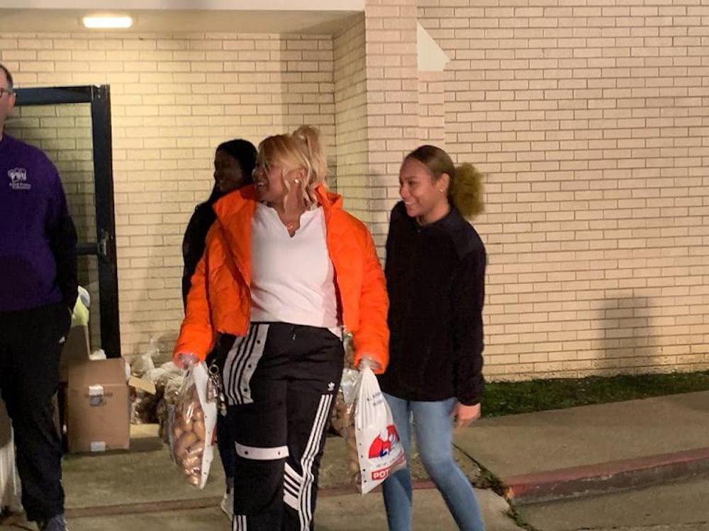 Two women walking down a sidewalk while holding onto bags.