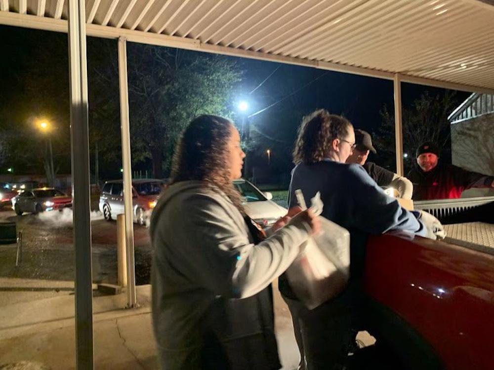 A woman standing next to another person holding onto some food.