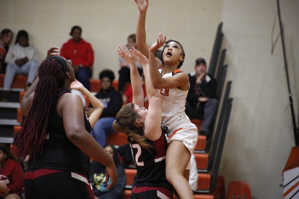 A girl is jumping in the air to catch a basketball.