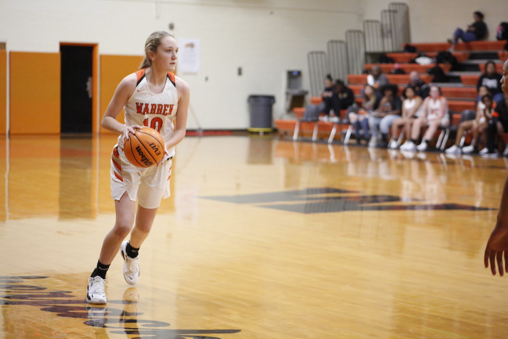 A girl is holding a basketball on the court