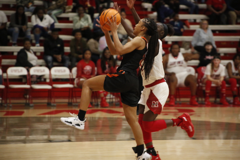 A woman in black and white basketball uniform playing basketball.