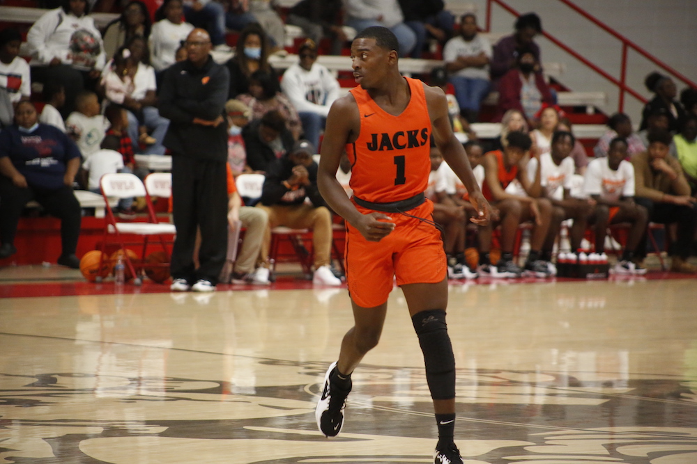 A basketball player in an orange uniform is playing basketball.