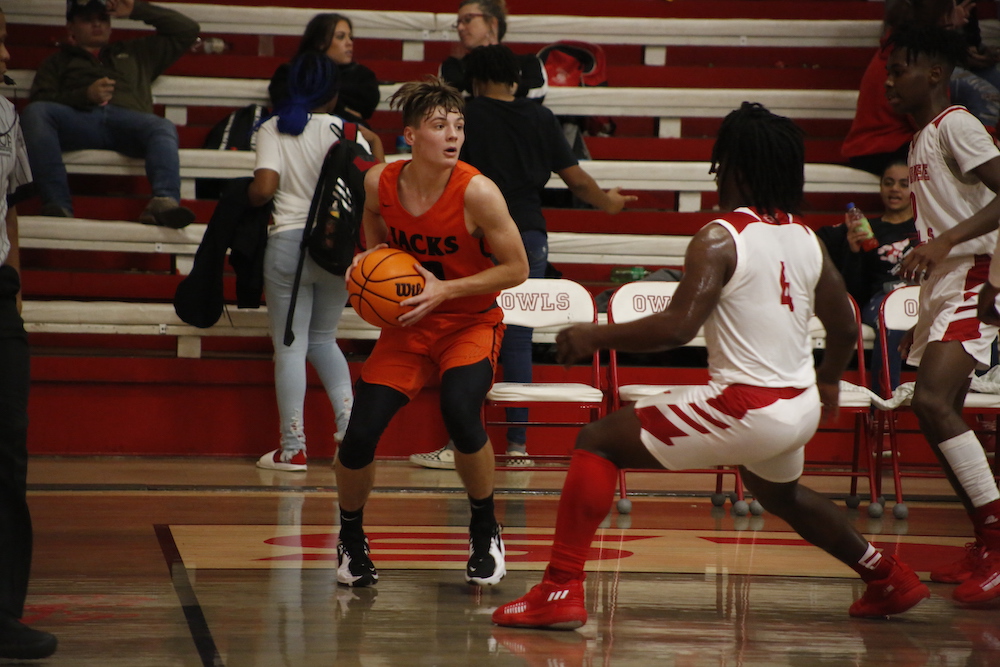 A boy in an orange and white uniform holding a basketball.