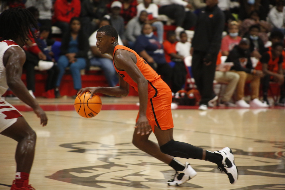 A man in an orange uniform dribbles the ball.