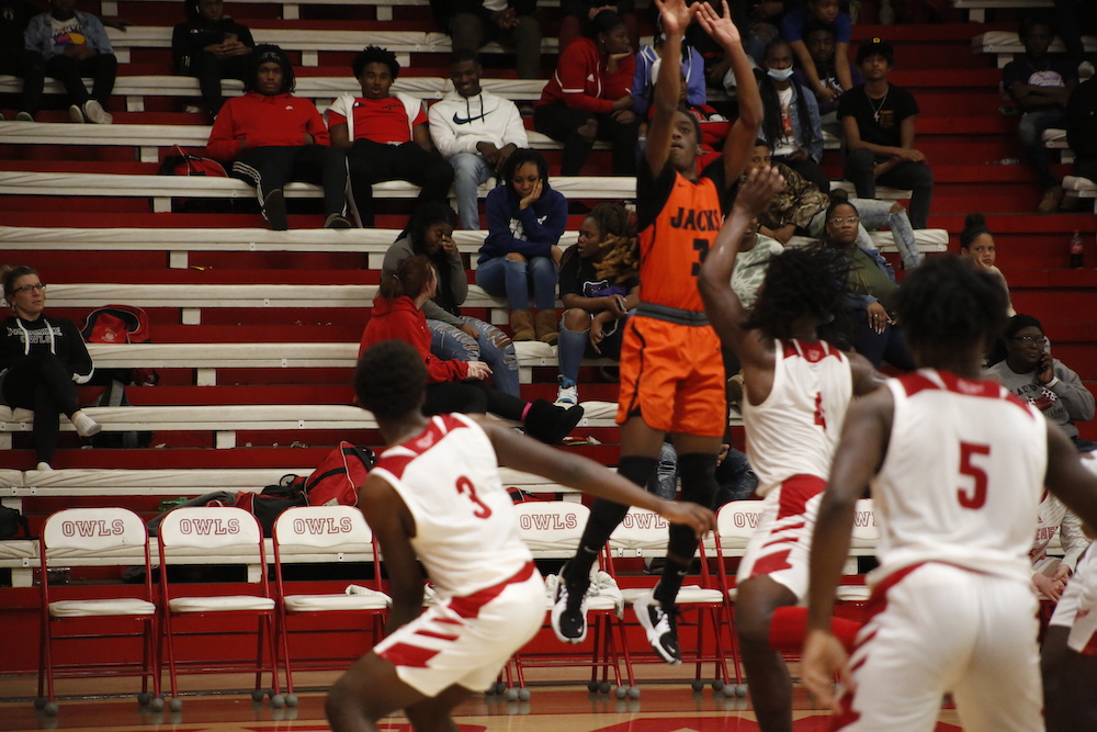 A group of men playing basketball in front of an audience.