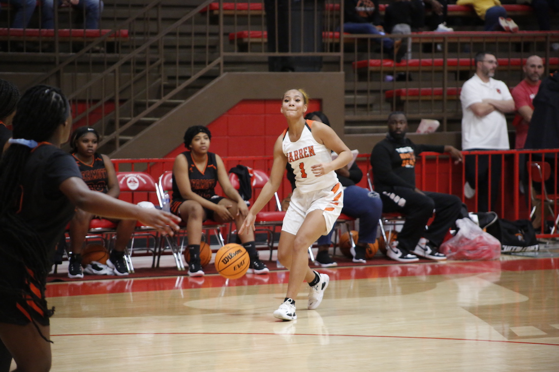 A girl dribbles the ball during a basketball game.