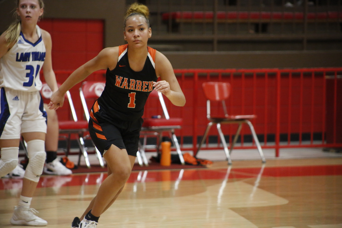 A girl in black and orange basketball uniform running on the court.