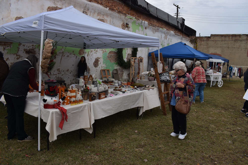 A woman standing next to an outdoor market.