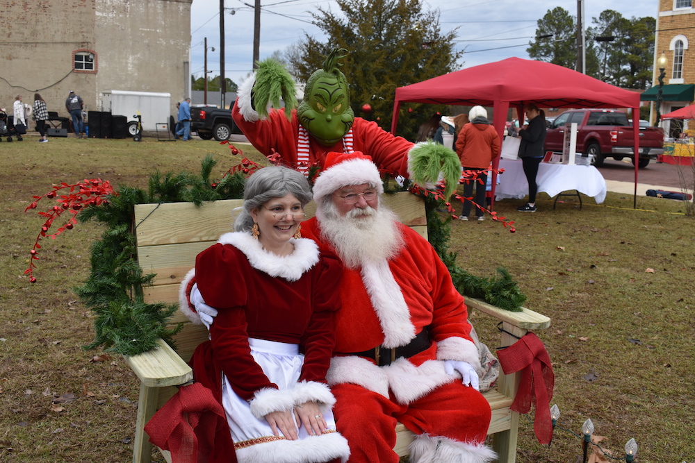 Two people dressed as santa and the grinch