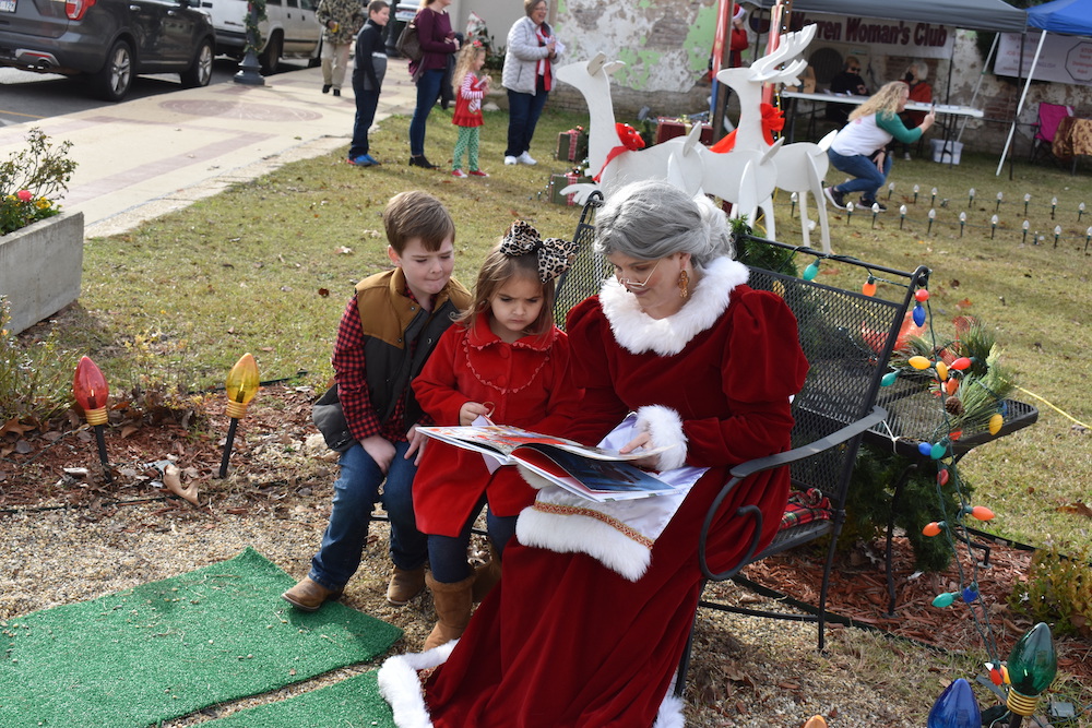 A woman dressed as santa claus reading to children.
