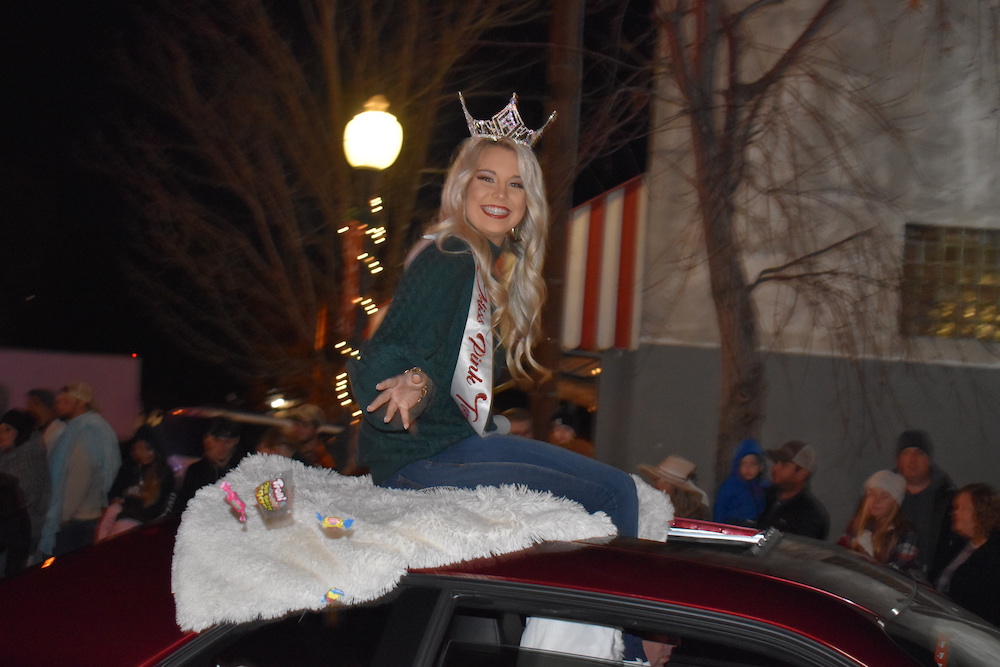 A woman sitting on the hood of a car at night.