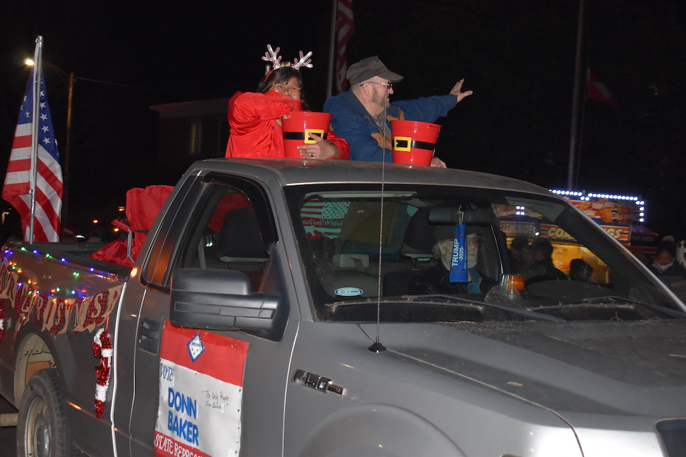 A man in the back of a truck with two people on top.