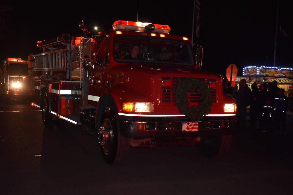 A fire truck is driving down the street at night.
