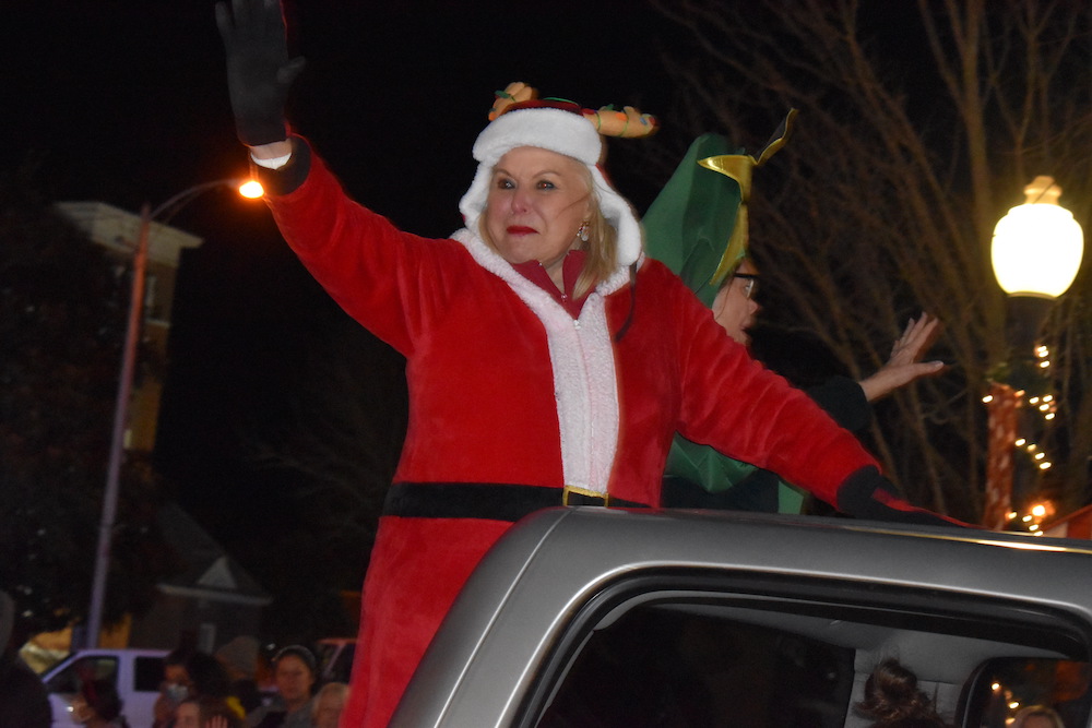 A woman in a red and white costume riding on the back of a truck.