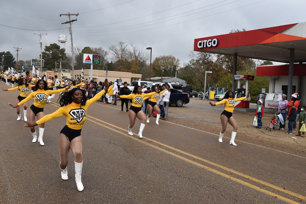 A group of cheerleaders are marching down the street.