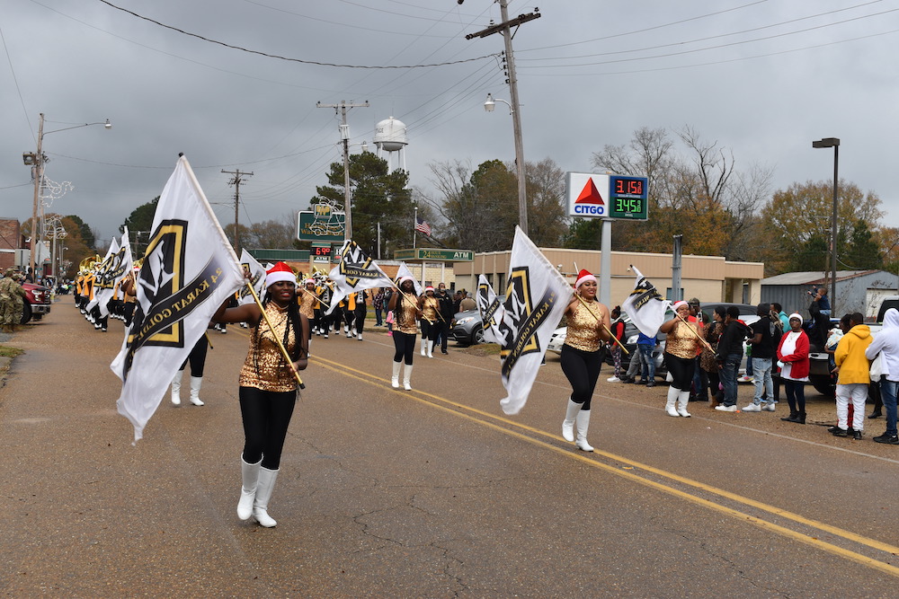 A parade with marching band in the middle of street.