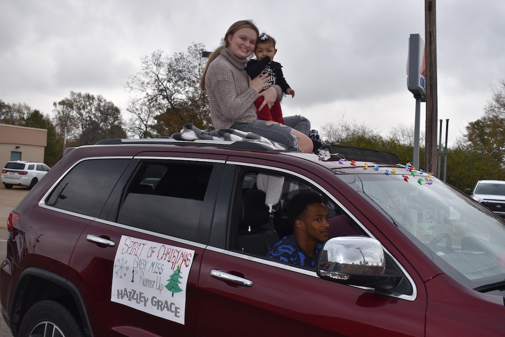 A woman and two children sitting on the hood of a car.