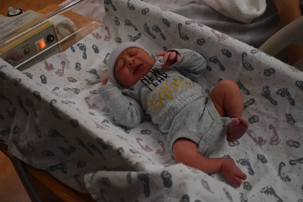 A baby is laying in a bed with sheets.