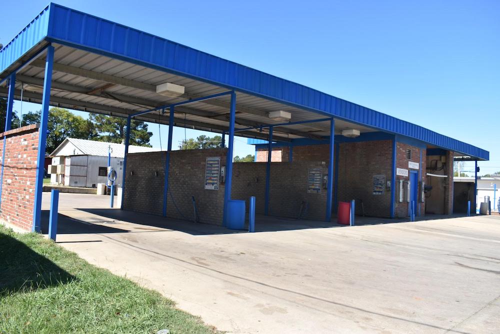 A blue building with a parking lot in the background.