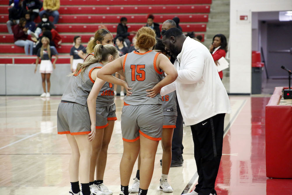 A group of women standing on top of a basketball court.