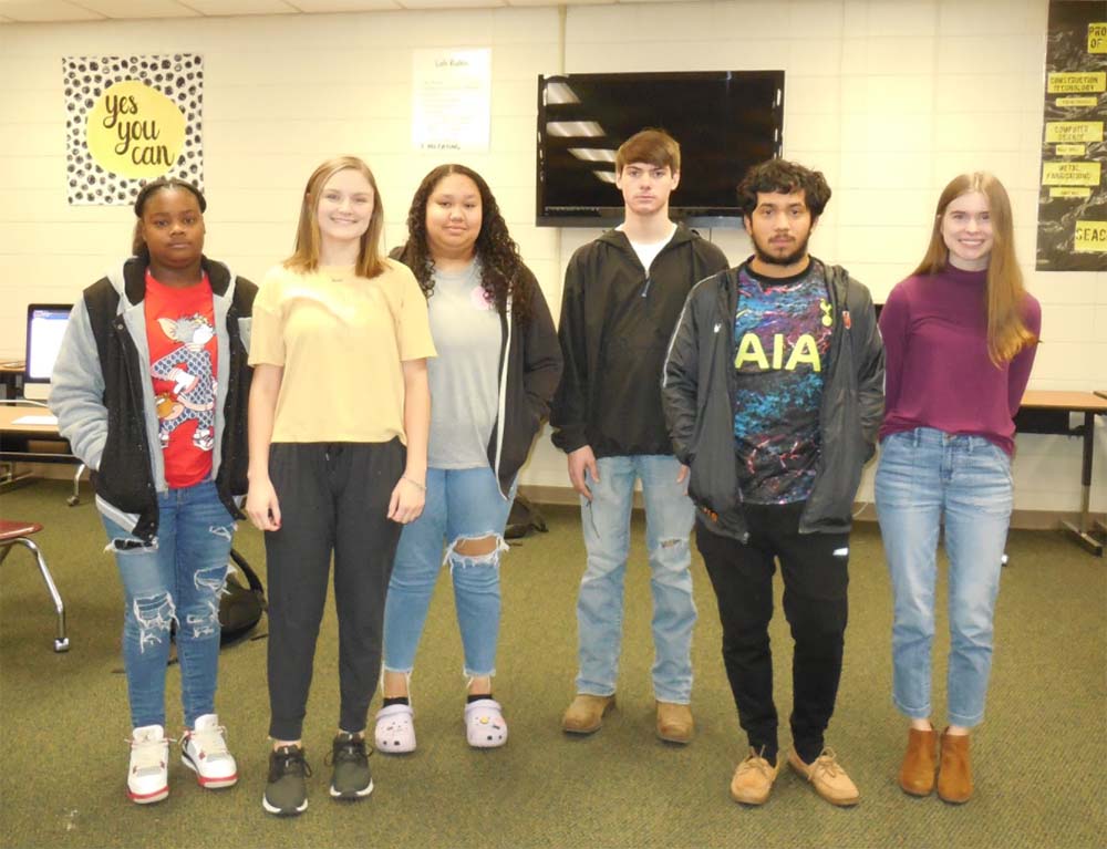 A group of people standing in front of a tv.