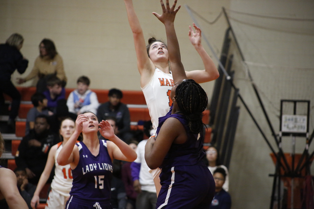 A group of people watching two girls play basketball.