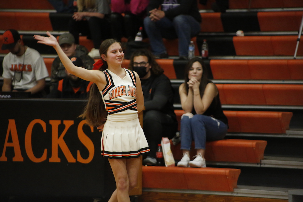 A girl in cheerleader uniform waving to the crowd.
