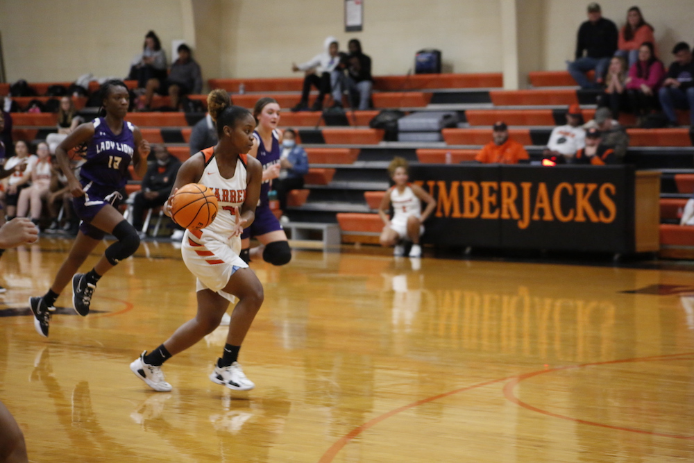 A girl dribbles the basketball on a court.