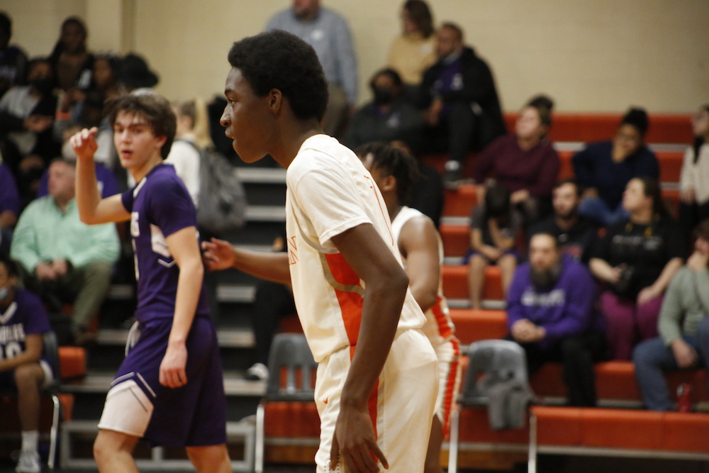 A group of young men playing basketball in front of an audience.