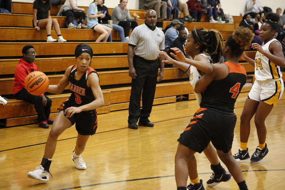 A group of girls playing basketball in front of an audience.