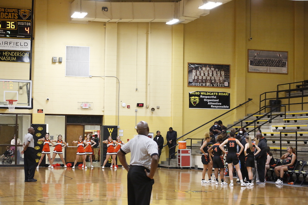 A group of people standing on top of a basketball court.