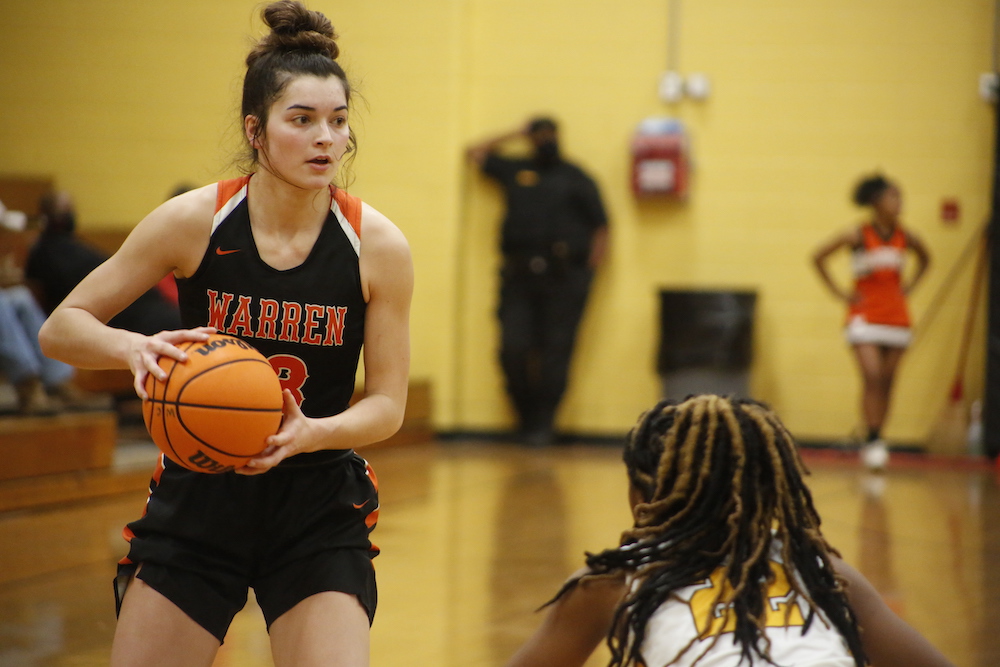 A girl holding onto a basketball while standing on the court