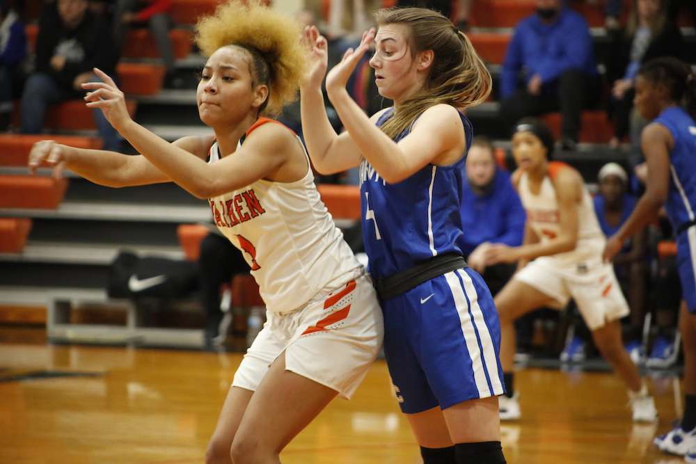 Two girls are playing basketball on a court.