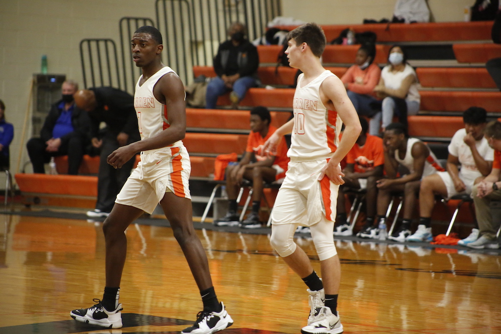 Two men are playing basketball on a court.
