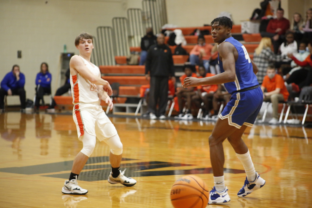 Two men playing basketball on a court with spectators watching.