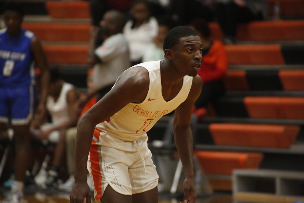 A man in white shirt and shorts playing basketball.