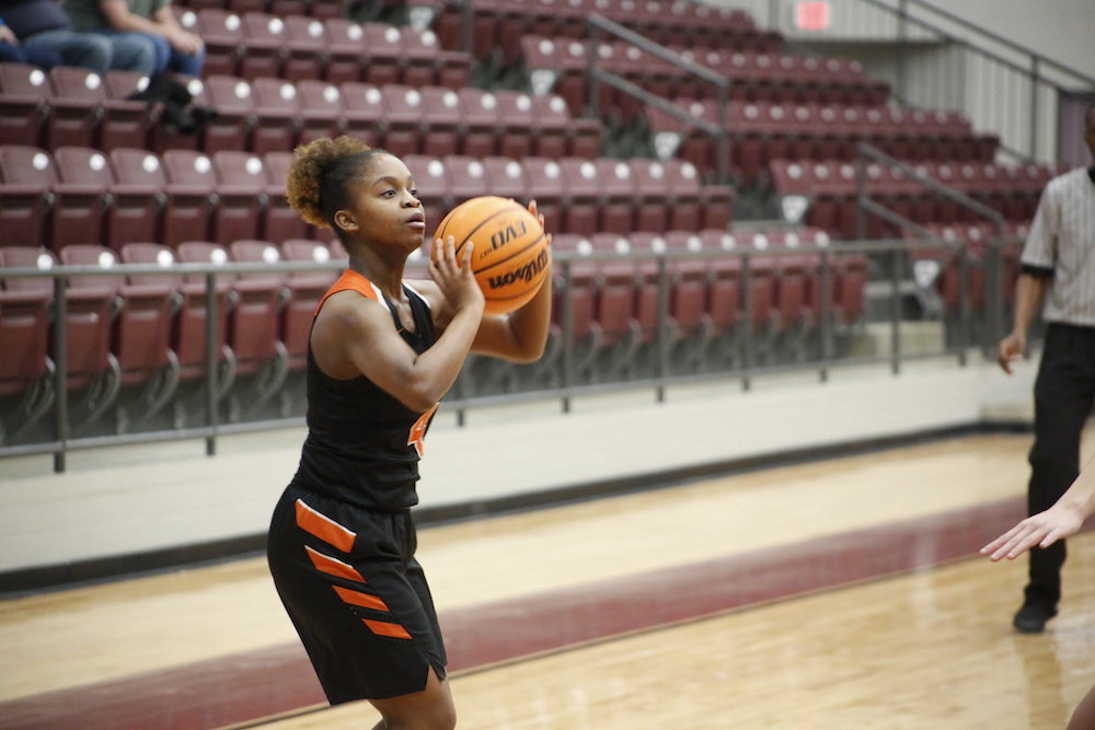A woman holding onto a basketball in front of an audience.