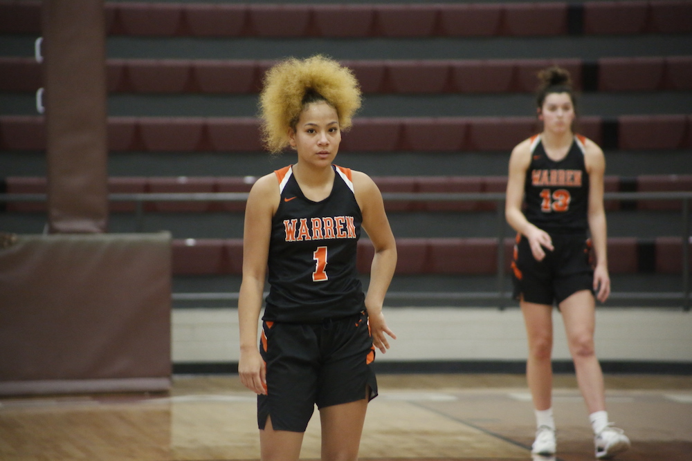 A girl with blonde hair stands on the court.