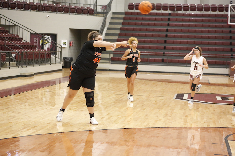 A group of people playing basketball on an indoor court.