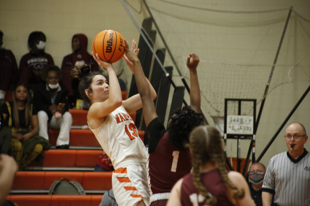 A basketball player is jumping up to hit the ball.