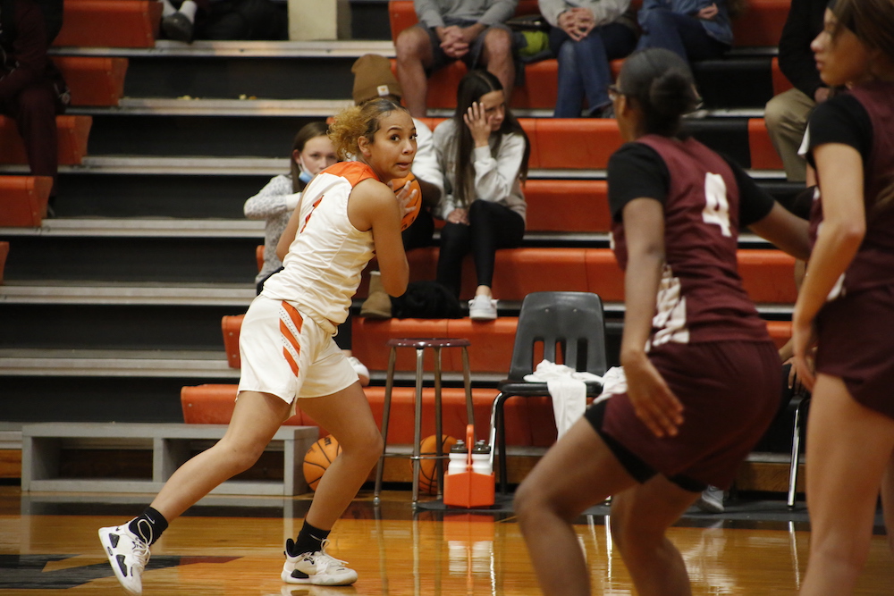A girl in orange and white playing basketball.
