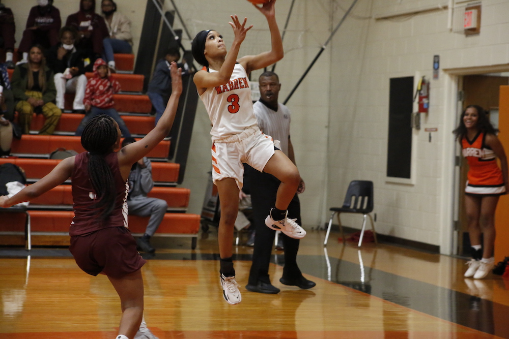 A girl is jumping up to the air with her basketball.
