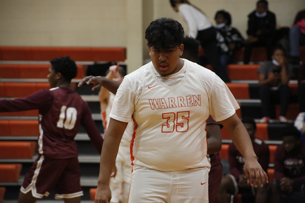 A man in white shirt standing on basketball court.