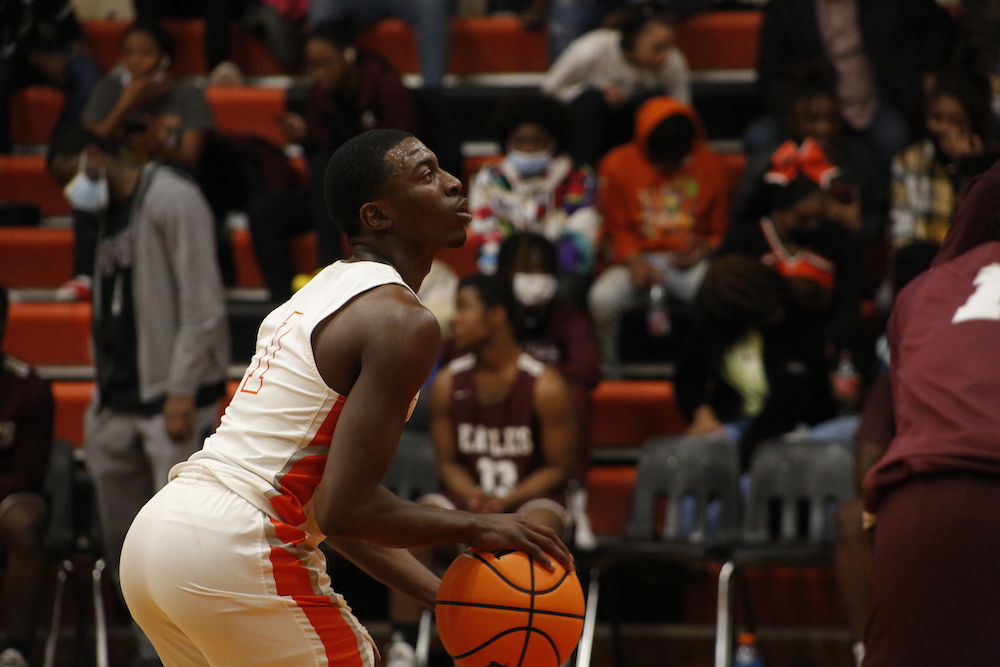 A young man holding onto a basketball in front of an audience.