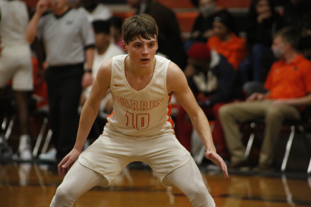 A young man in white shirt playing basketball.