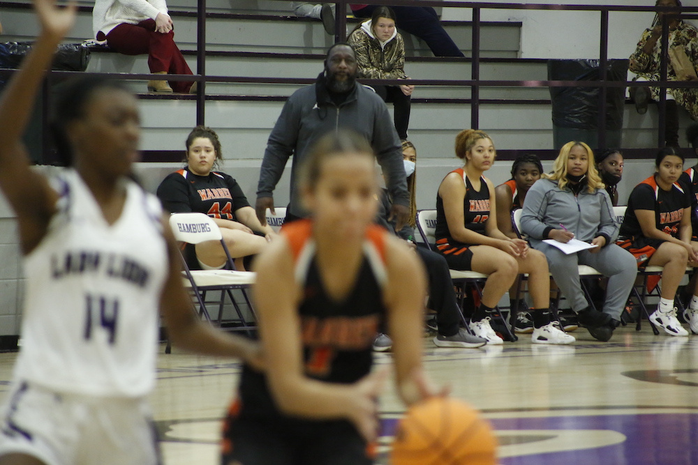 A group of people watching some girls play basketball.